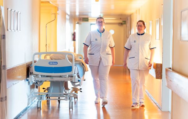 2 verpleegkundigen lopen in ziekenhuisgang