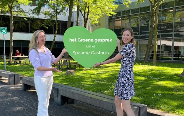 twee leden van de bestuurlijke inspiratie commissie duurzaamheid houden groen hart vast met de tekst het groene besprek bij het spaarne gasthuis
