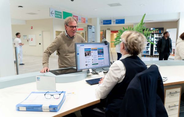 Patiënt staat bij de informatiebalie van het ziekenhuis