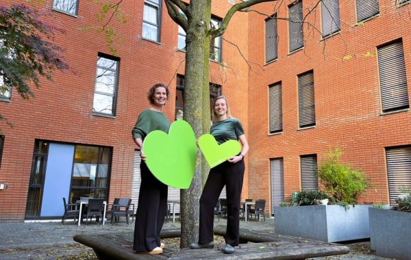 Tamara Kroll en Lieke Hettema staan op een boombank met het groene hart