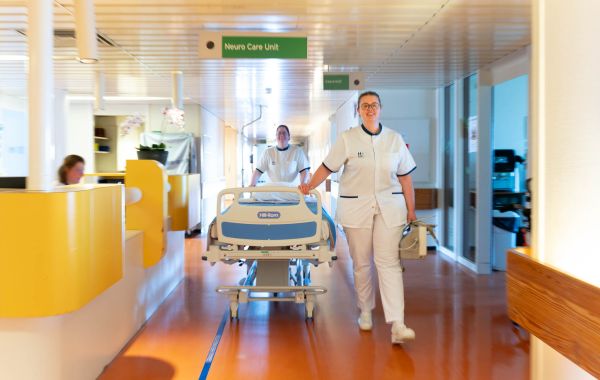 2 verpleegkundigen lopen in ziekenhuisgang