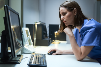 Zorgverlener aan bureau kijkend naar pc scherm