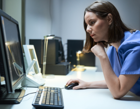 Zorgverlener aan bureau kijkend naar pc scherm