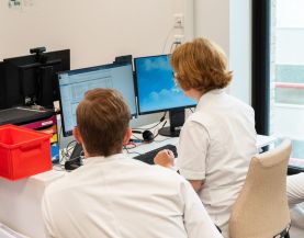 Twee zorgprofessionals achter beeldscherm